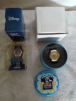 Overview showing both Disney watches with their boxes and tin