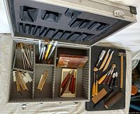 Overview of open aluminum case showing compartments filled with carving tools and boxed knife set