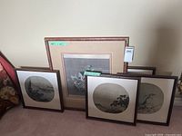 Five framed prints leaning against wall showing group