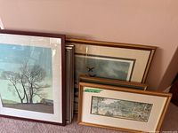 Group of six framed artworks leaning against wall
