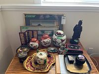 Overview of all items on table including ginger jars, lacquerware, porcelain pieces, artwork and statue