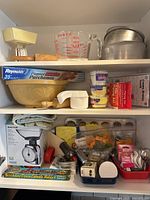 Cabinet shelves with scales, Pyrex jug, ceramic bowl, parchment, liners and tools visible