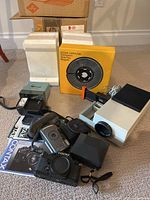 Lot overview showing Agfa slide projector, Kodak carousel tray, Contax camera, flash, manuals and accessories