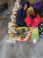 Group shot of boxed stove, hammock, chairs, backpack, propane cylinders and other items