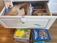 Drawer with paper napkins, basket of linens, placemats and cookbooks stack below