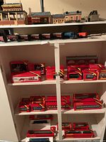 Cabinet shelves with numerous red Hornby boxes and loose rolling stock on top