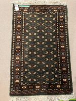 Full view of moss green Bokhara rug with fringe