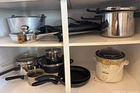 Shelf view showing pressure cooker, electric grill, roasting pot, saucepots, saucepan, frying pans and Crock-Pot