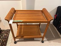 Full view of solid wood two-tier tea trolley on casters