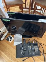 Two Samsung TVs, remotes, DVD player and accessories on floor