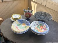 Lot overview showing bowls, jug, cast iron stand and stacked saucers