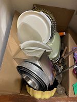 Overview of box showing Tupperware containers, nested mixing bowls, yellow bundt mould and other bakeware