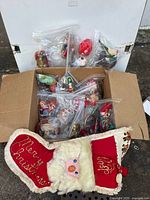 Box with assorted bagged ornaments and Santa stocking
