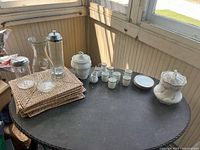 Overview of all items on table: porcelain espresso set, lidded dishes, glassware, placemats