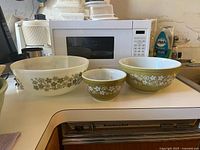 Three Pyrex Daisy Chain bowls showing sizes and colors