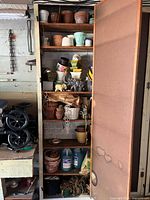 Full cabinet view showing all pots, planters, antifreeze jugs, rope