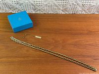 Full view of chain, hang tag and Birks box on tabletop