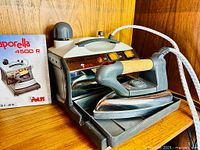 Steam iron on boiler base with manual