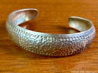 Full view of hammered sterling silver cuff bracelet on tabletop
