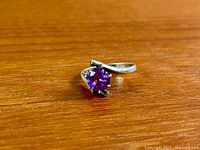 Close-up of ring showing bypass band and purple gemstone