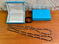 Two necklaces, bracelet, and Birks boxes displayed on table
