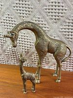 Adult and baby brass giraffes on wooden surface