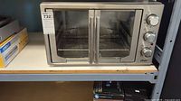 Front view of Oster stainless steel French-door convection oven on shelf