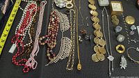 Overview of necklaces, brooches, rings, bracelets laid out on dark fabric
