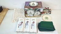 Overview of entire lot on table: boxed Fairy Godmothers, Spode plates, napkins, frame, linens