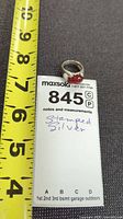 Ring beside measuring tape and tag showing handwritten Stamped Silver
