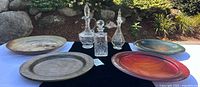 Overall lot showing three wood platters, ceramic platter, and three glass decanters with stoppers