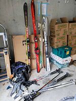 Overall view of four pairs skis, poles, boots, skates, backpack