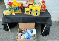 Overview of table with Fisher-Price playsets and box of McDonald’s toys