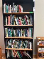 Full bookshelf showing five shelves packed with books