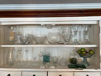 Cabinet shelf showing crystal candlesticks, bowls, pitcher, lidded dishes, vases and tray