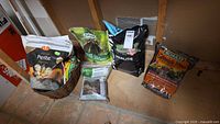 Group shot of five bags and seed packets against wall