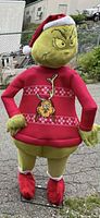 Rear view of 6-foot Grinch figure wearing Santa hat and red sweater with Max graphic