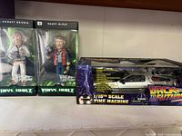 Front view of two Vinyl Idolz figures and boxed DeLorean model