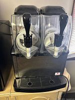 Front view showing twin clear hoppers, augers, black base and drip tray