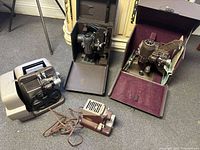 Overall view of four projectors: three larger units (two in cases, one freestanding) plus one small Standard projector in front