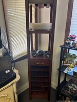 Full view of tall wooden wine rack tower with shelves and drawer