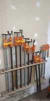 Rack holding 11 pipe bar clamps of varying lengths