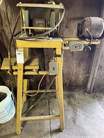 Full view of bench grinder on yellow stand with side motor