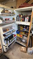Full refrigerator with shelves of assorted oils, lubricants, cleaners
