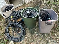 Overview of three plastic garbage cans filled with coiled heavy power cables