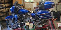 Full right-side view of blue Harley-Davidson Ultra Classic on red jack stand with loose parts in baskets