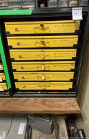 Front view of cabinet showing six yellow drawers in black frame