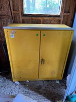 Front view of yellow metal cabinet showing two doors and handle