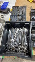 Top view of bin filled with chrome combination wrenches and nearby tool trays