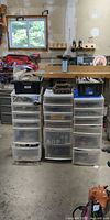 Wide view of three plastic drawer towers with bins and tools on top